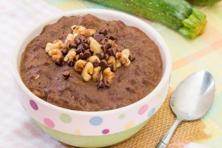 A bowl of chocolate zucchini oatmeal stopped with crushed nuts and chocolate chips.