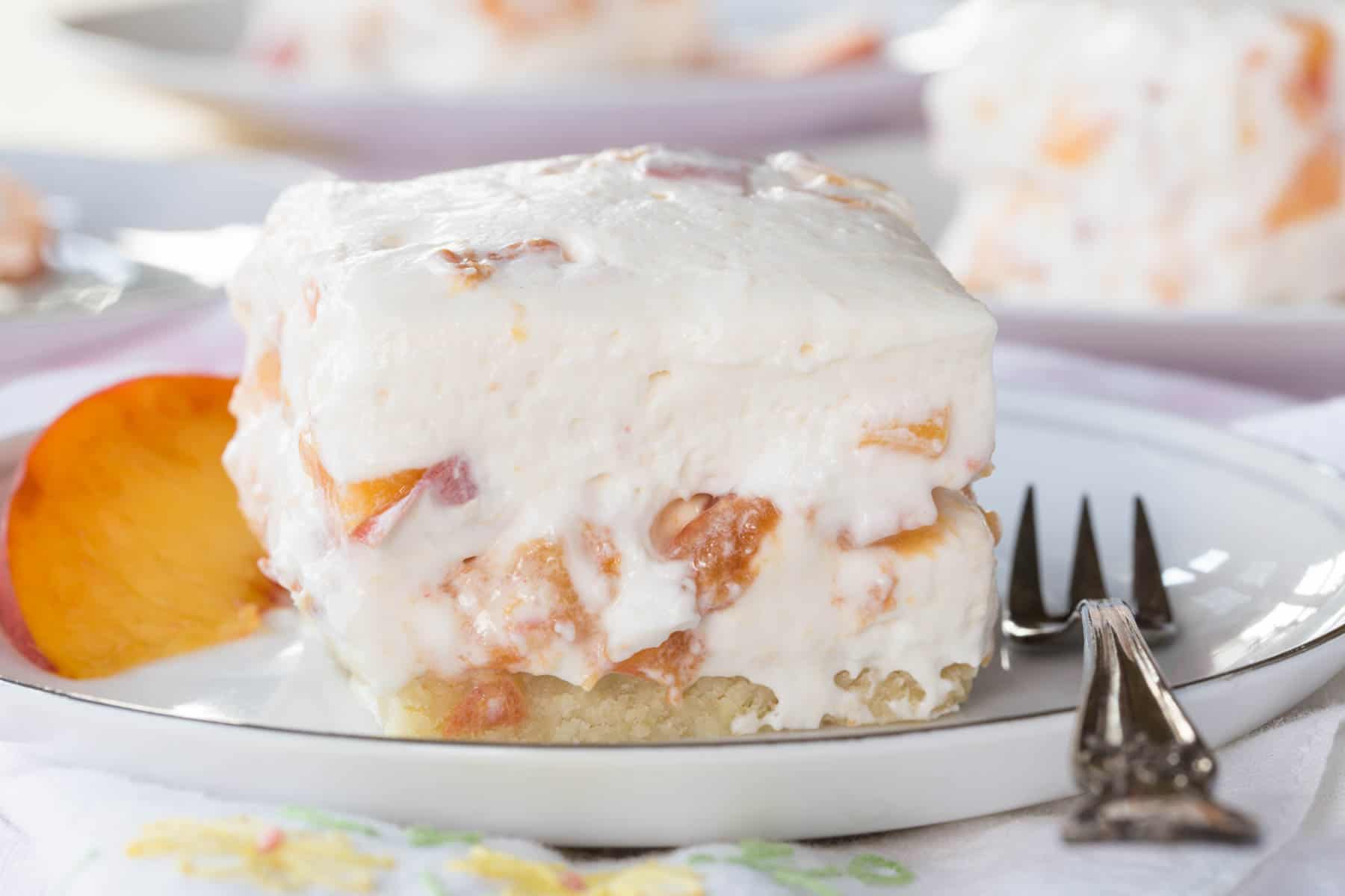 Fresh Peach Cheesecake Square on a white plate with a small fork