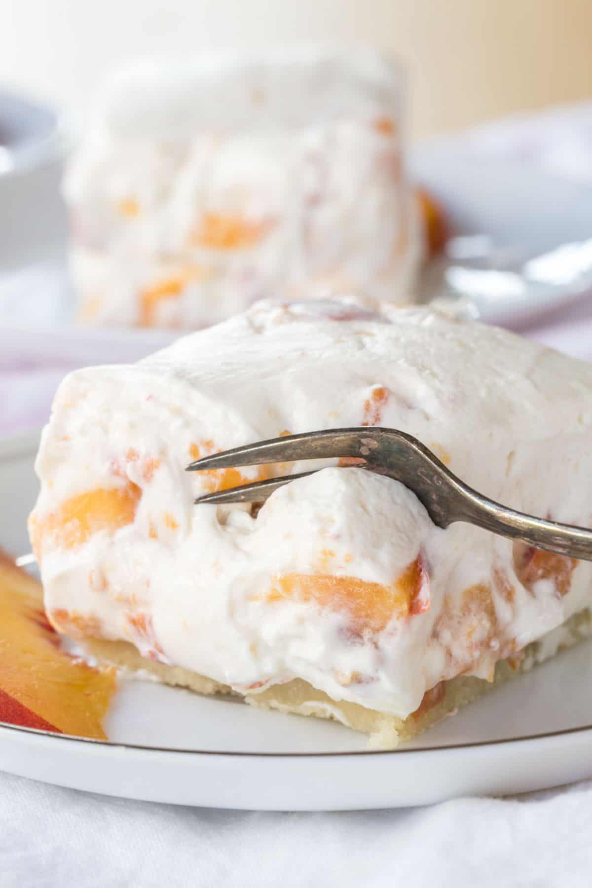 Cutting into a fluffy No Bake Gluten Free Peach Cheesecake Bar with a dessert fork