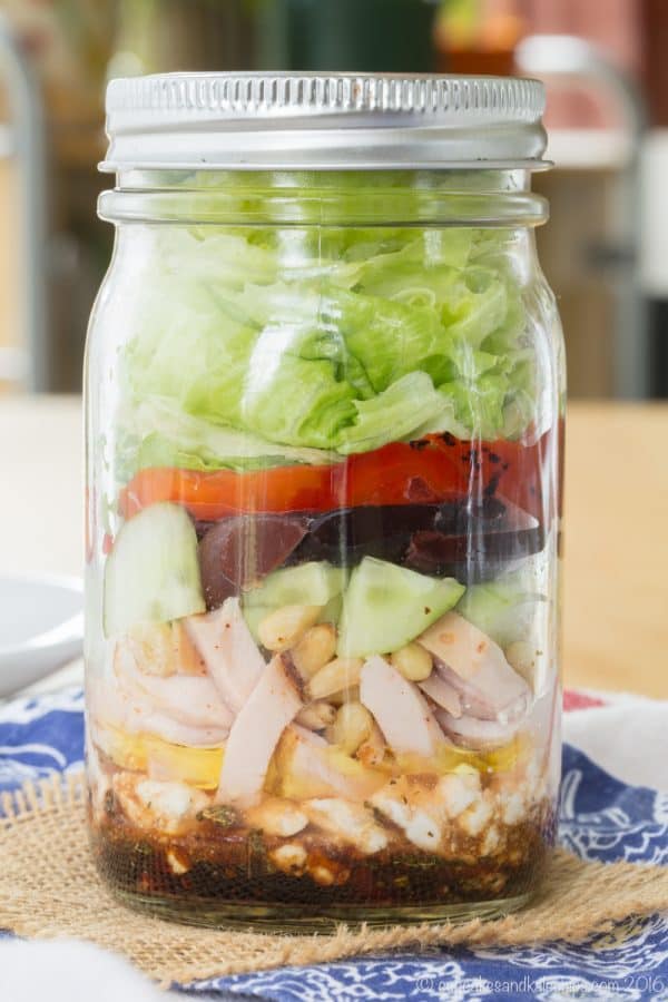 Mediterranean Turkey Mason Jar Salad - layer a simple salad dressing, feta cheese, turkey, veggies, and more for an easy and portable lunch recipe with @jennieorecipes. Gluten free and low carb. #ad | cupcakesandkalechips.com