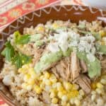 Slow Cooker Peruvian Pulled Pork served over cauliflower rice with corn, a drizzle of aji sauce, and crumbled queso fresco.