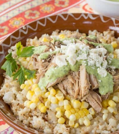 Slow Cooker Peruvian Pulled Pork served over cauliflower rice with corn, a drizzle of aji sauce, and crumbled queso fresco.