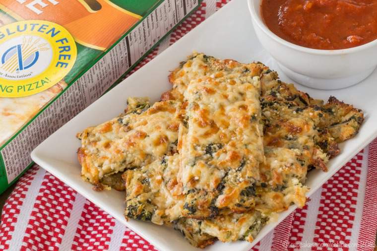 A white dish of Cauliflower Breadsticks with a bowl of tomato sauce