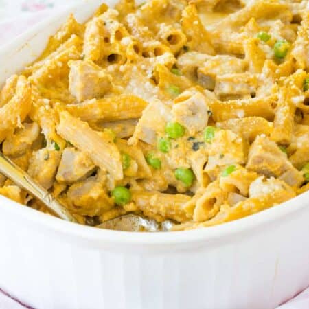 Creamy pumpkin penne with chicken sausage is spooned from a baking dish.