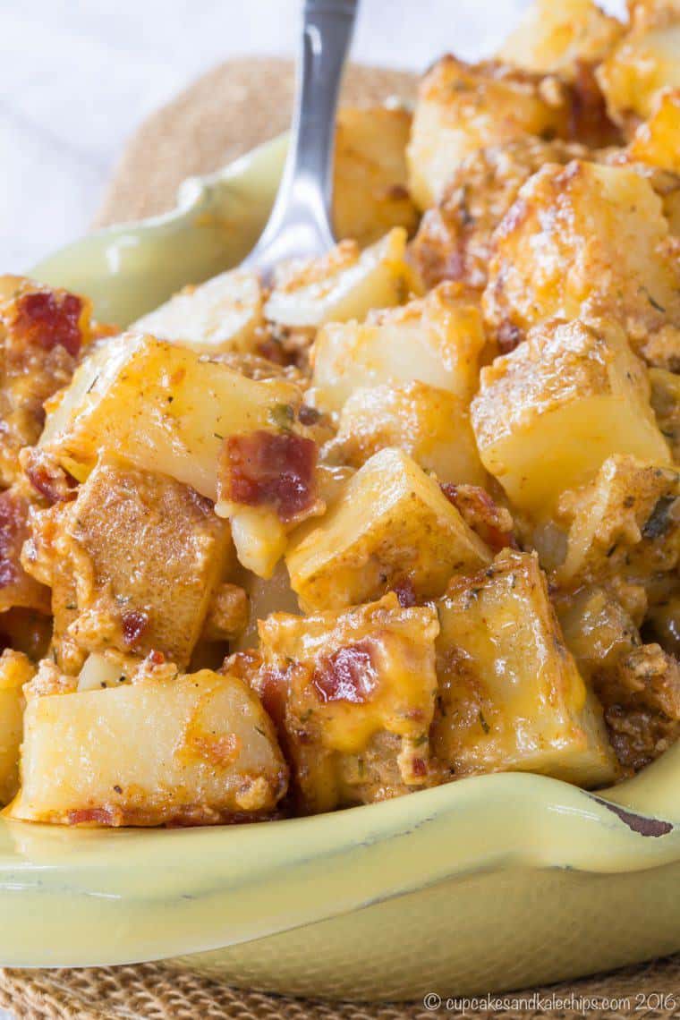 Cubed potatoes covered in melted cheese and crumbled bacon