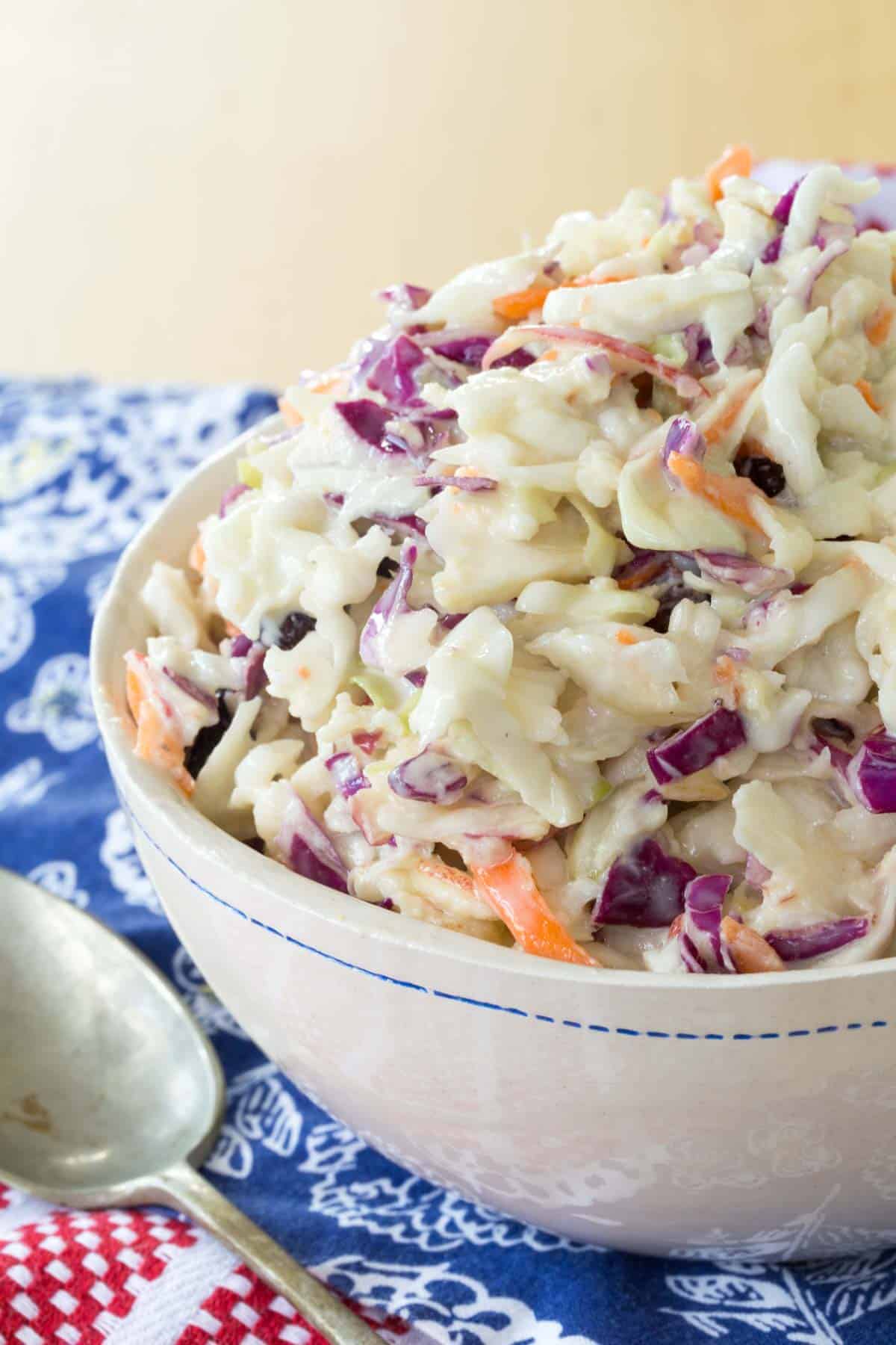 apple coleslaw in a white serving bowl with a blue decorative edge