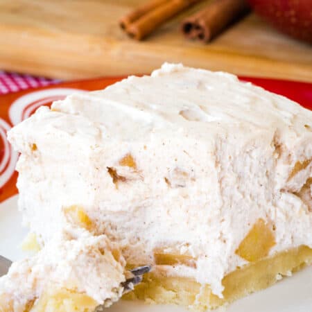 An Apple Cheesecake Bar with a bite removed and on the fork resting in front of it.