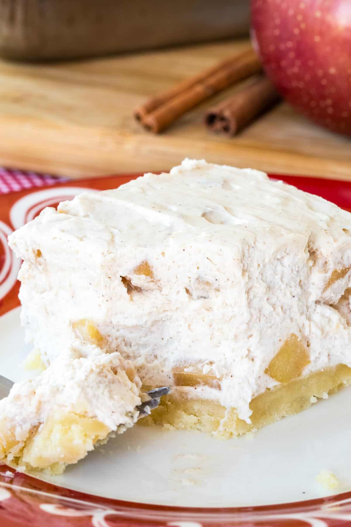 An Apple Cheesecake Bar with a bite removed and on the fork resting in front of it.