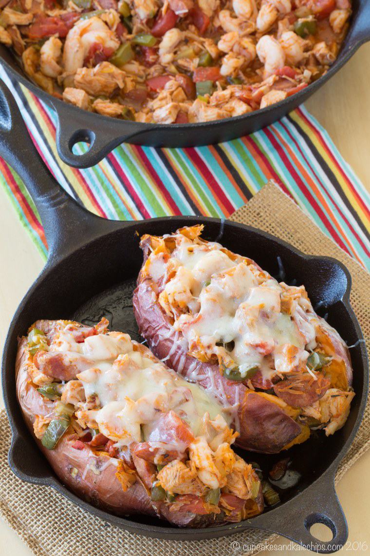 Two jambalaya stuffed sweet potatoes in a cast iron skillet