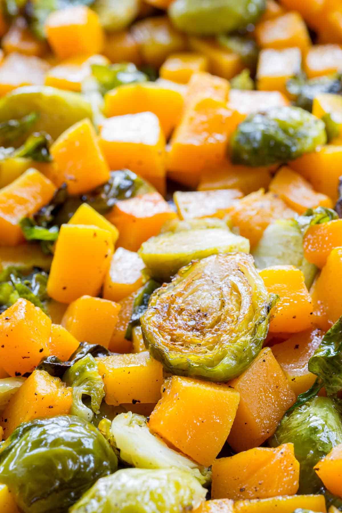 Closeup of the cubed butternut squash and halved Brussels sprouts roasted on a sheet pan.