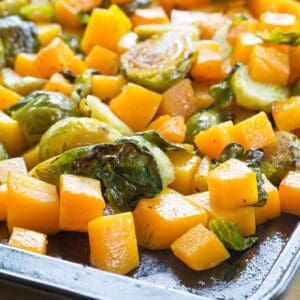 Maple roasted Brussels sprouts and butternut squash cubes on a baking sheet.