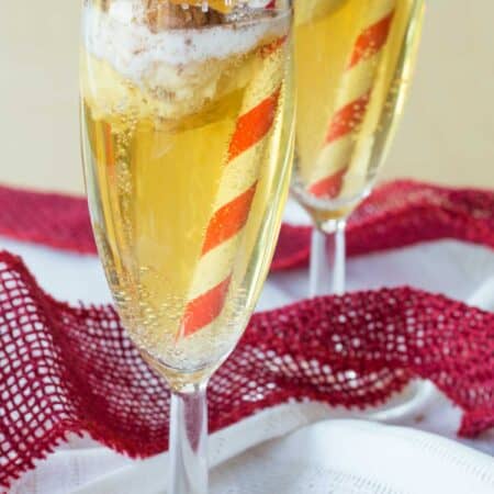 Two flutes of sparkling cider with a small scoop of ice cream floating in them.