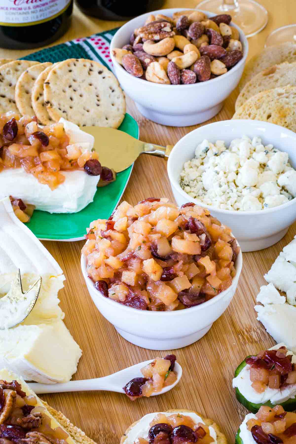 A small white bowl of apple chutney in the middle of a cheese board.