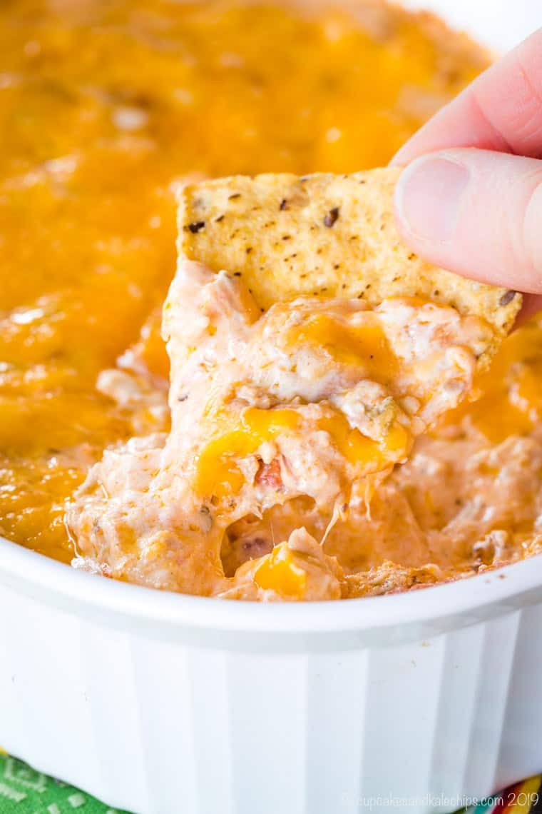 scooping up cheesy jambalaya dip with a tortilla chip