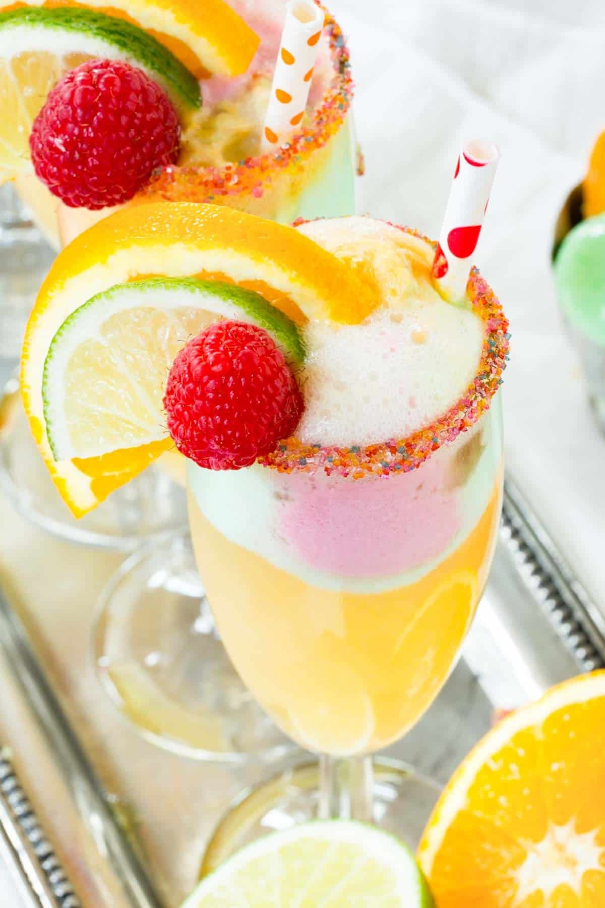 A Sparkling Cider Sherbet Float with Rainbow Sugar on the Rim of the Glass and Fresh Fruit Garnishes