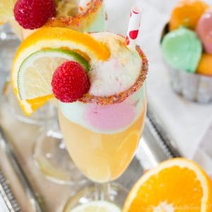 Sparkling Cider Rainbow Sherbet Float garnished with orange and lime slices and a raspberry