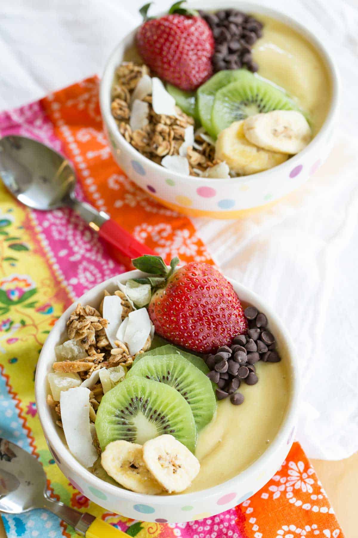 two smoothie bowls sitting on brightly colored napkins