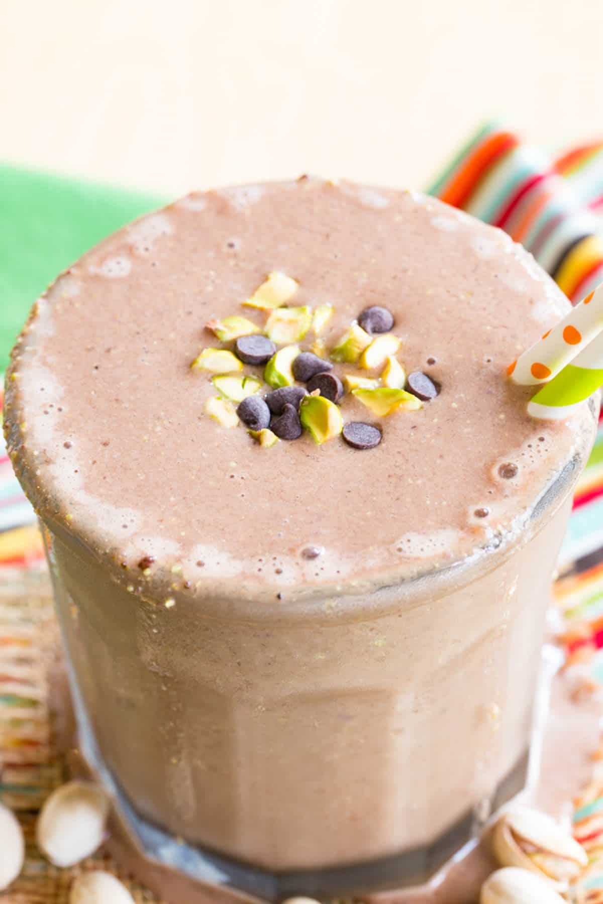 A closeup of the chocolate chip and pistachio garnish on top of a chocolate smoothie.