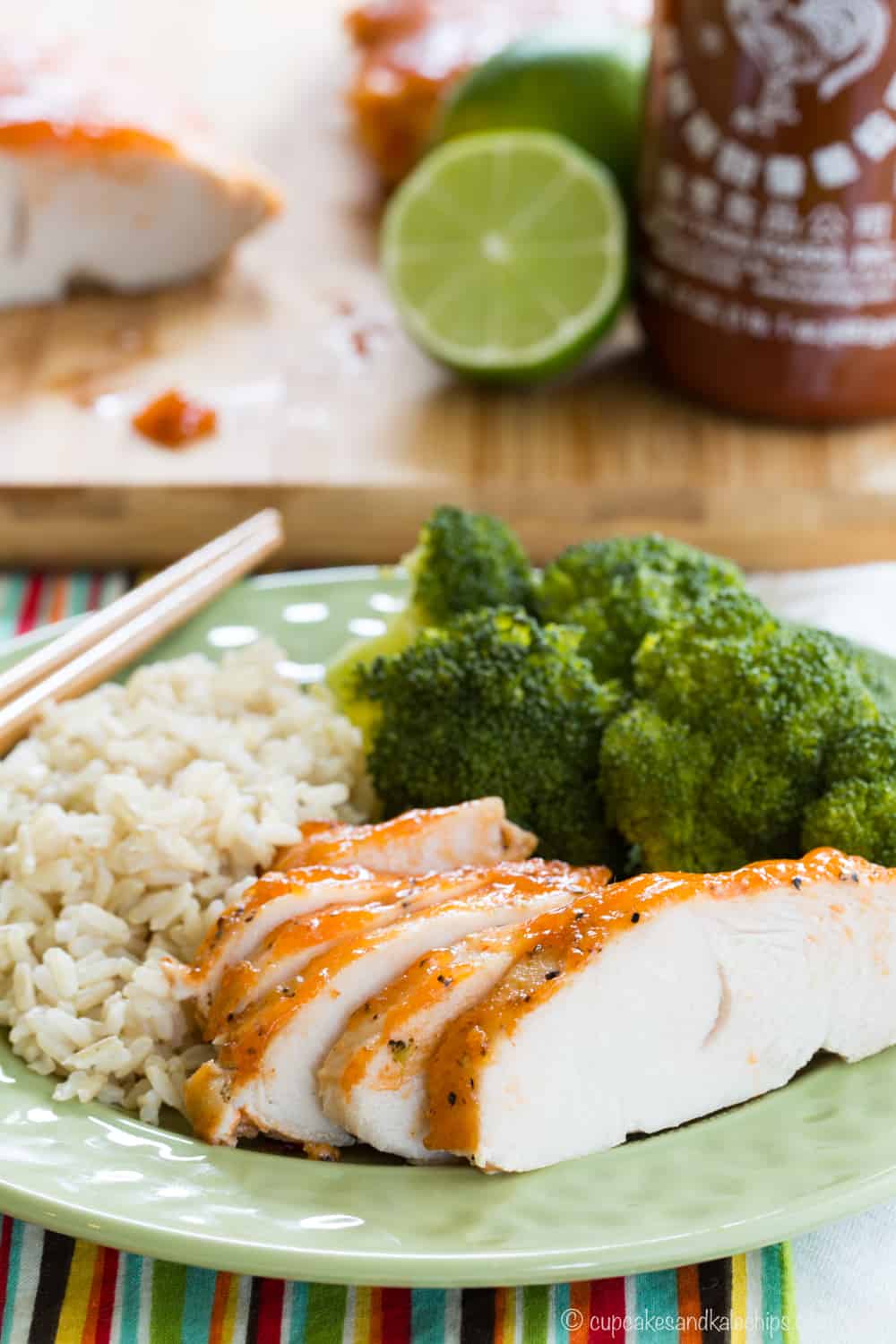 Sliced crockpot turkey breast tenderloin served on a green plate with brown rice and broccoli.