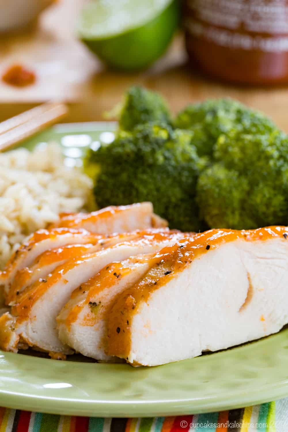 Closeup of slices of sriracha lime crockpot turkey tenderloin on a green plate.