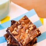 A stack of three Flourless Peanut Butter Cup Brownies on a striped napkin with text overlay that says "Gluten Free Reese's Brownies".