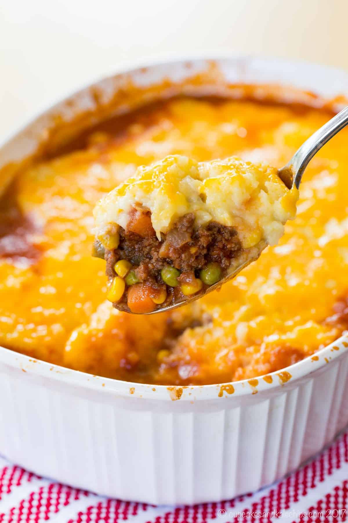 a spoonful of shepherds pie held up over a casserole dish