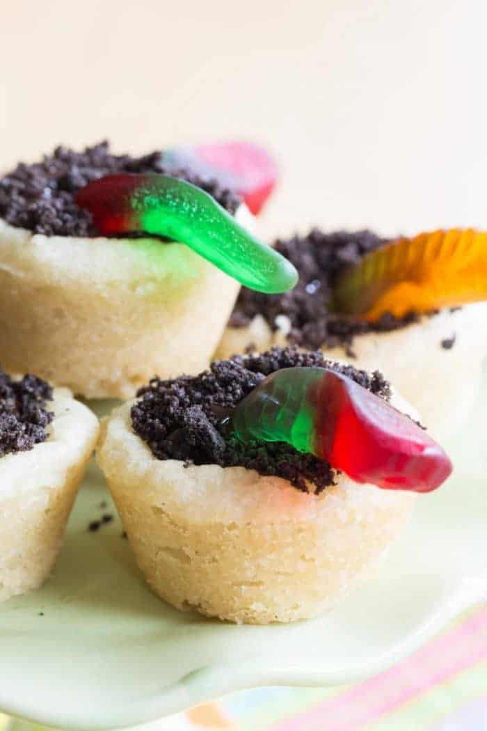 Gummy worms sticking out of a cookie cup with chocolate ganache and crushed Oreos