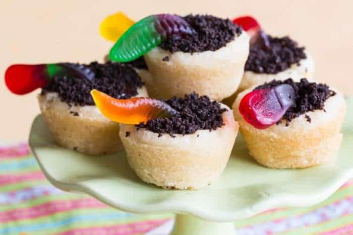 A small cake pedestal with worms and dirt sugar cookie cups