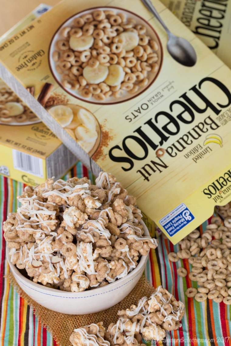 A bowl of gluten-free Banana Nut Cheerios popcorn snack mix next to a box of Cheerios.