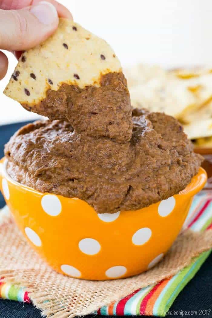 Dipping a tortilla chip into Pumpkin Black Bean Hummus