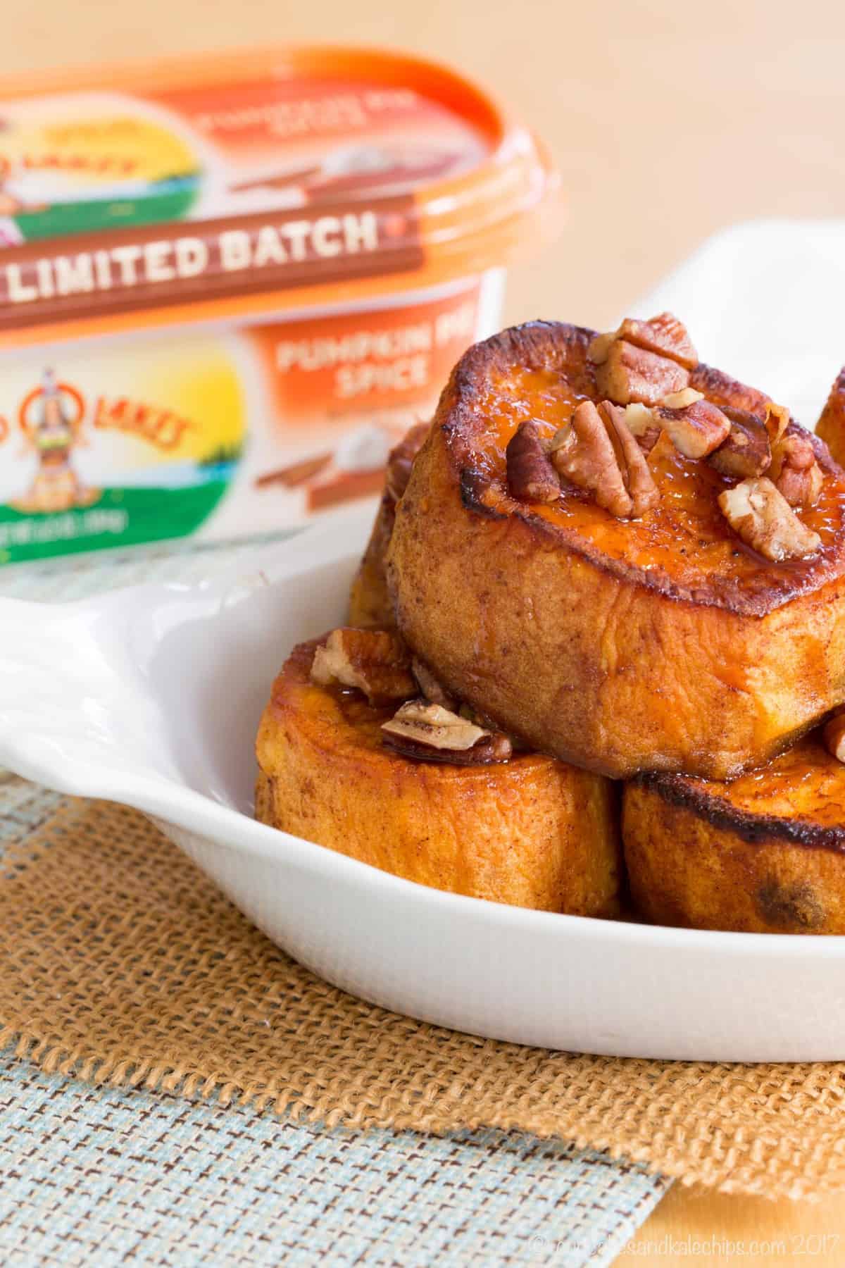 Melting sweet potatoes wth pecans on a dish with pumpkin spice butter in the background