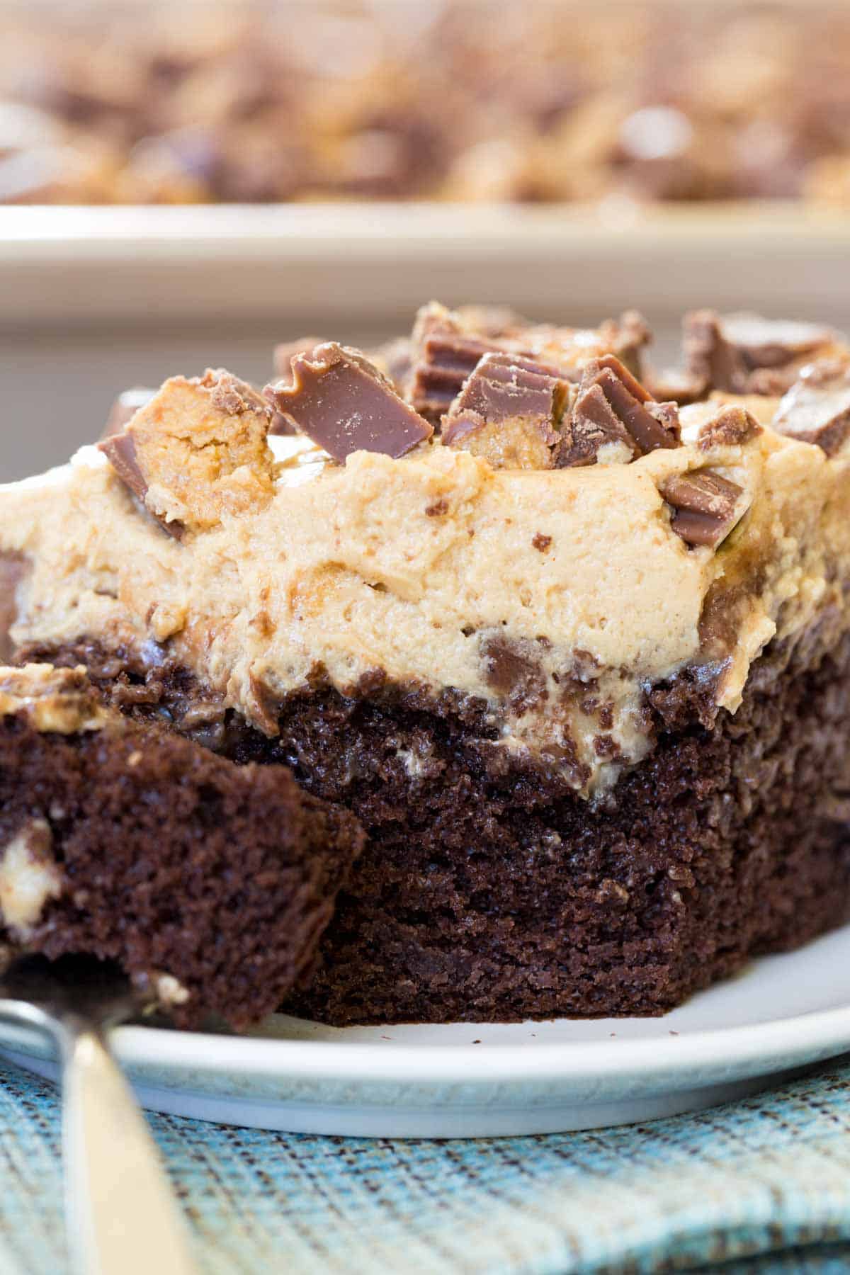 A closeup of the corner of a piece of Reese's poke cake where a bite has been removed.