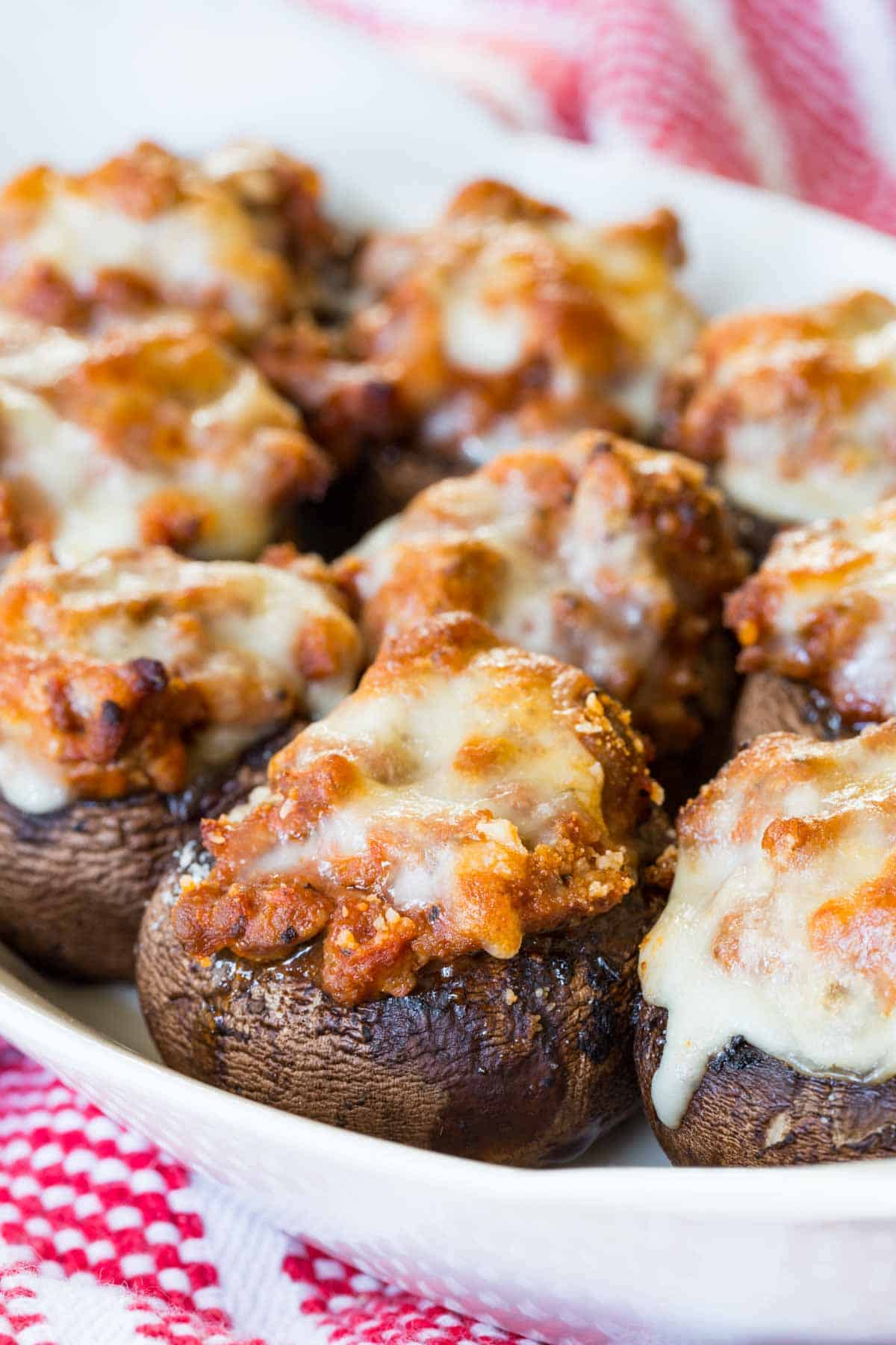 A serving dish with ground beef stuffed mushrooms topped with melted cheese.