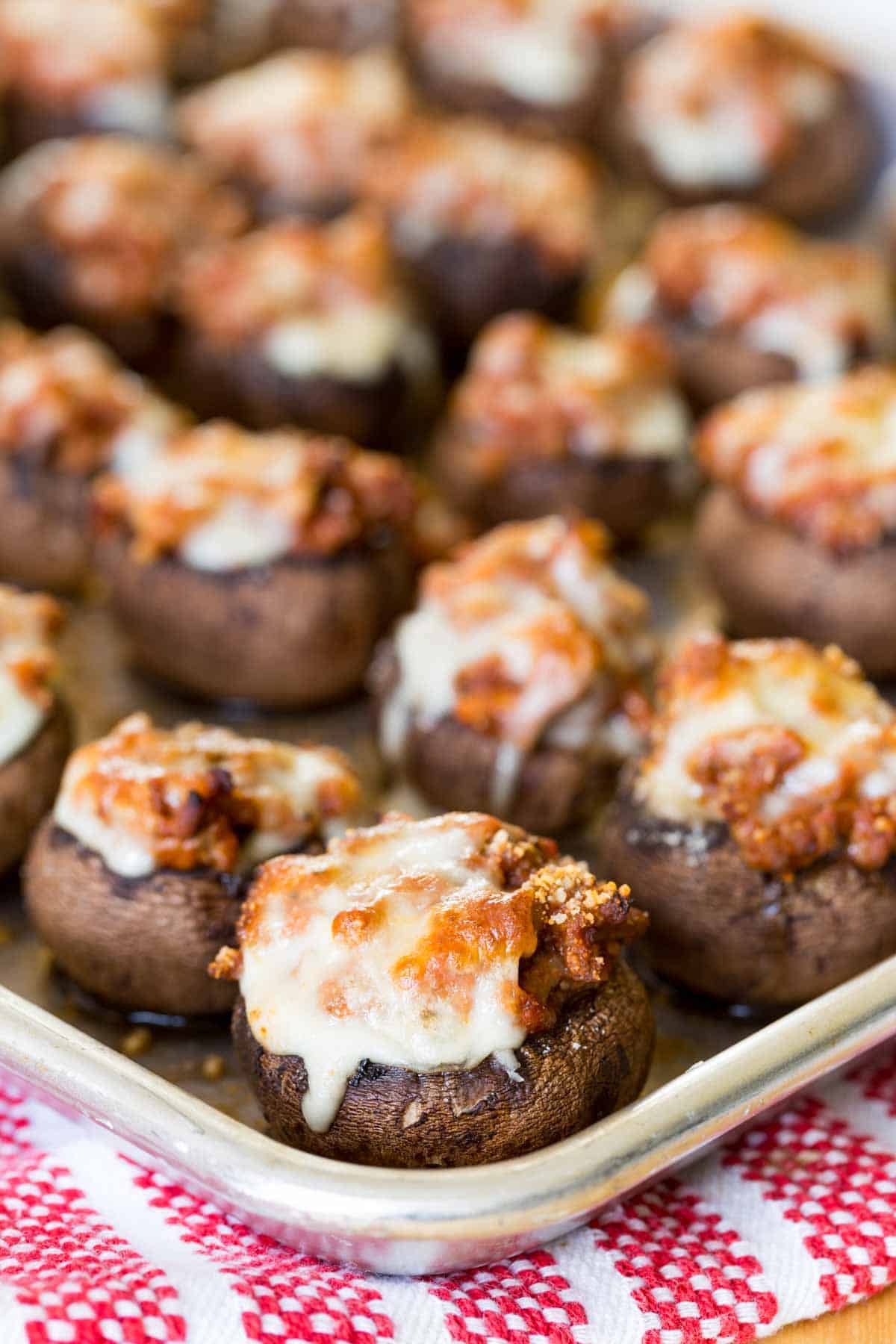 A sheet pan of stuffed mushrooms with mozzarella cheese.