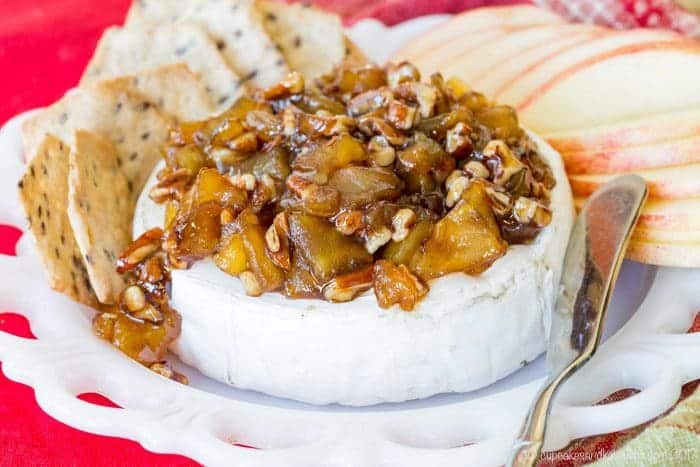 Caramelized Apple Pecan Baked Brie is served surrounded by crackers