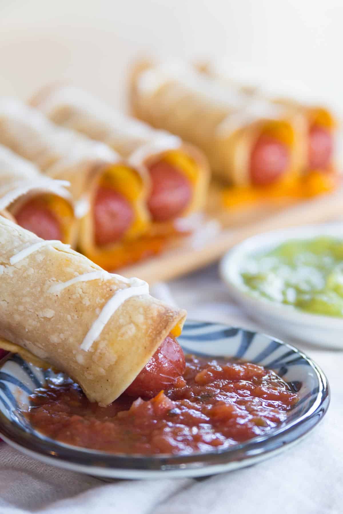 One of the crispy dogs being dipped in salsa.