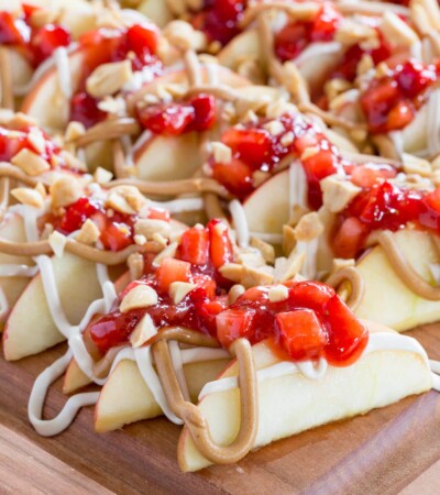 slices of apples topped with peanut butter and strawberry jam on a cutting board