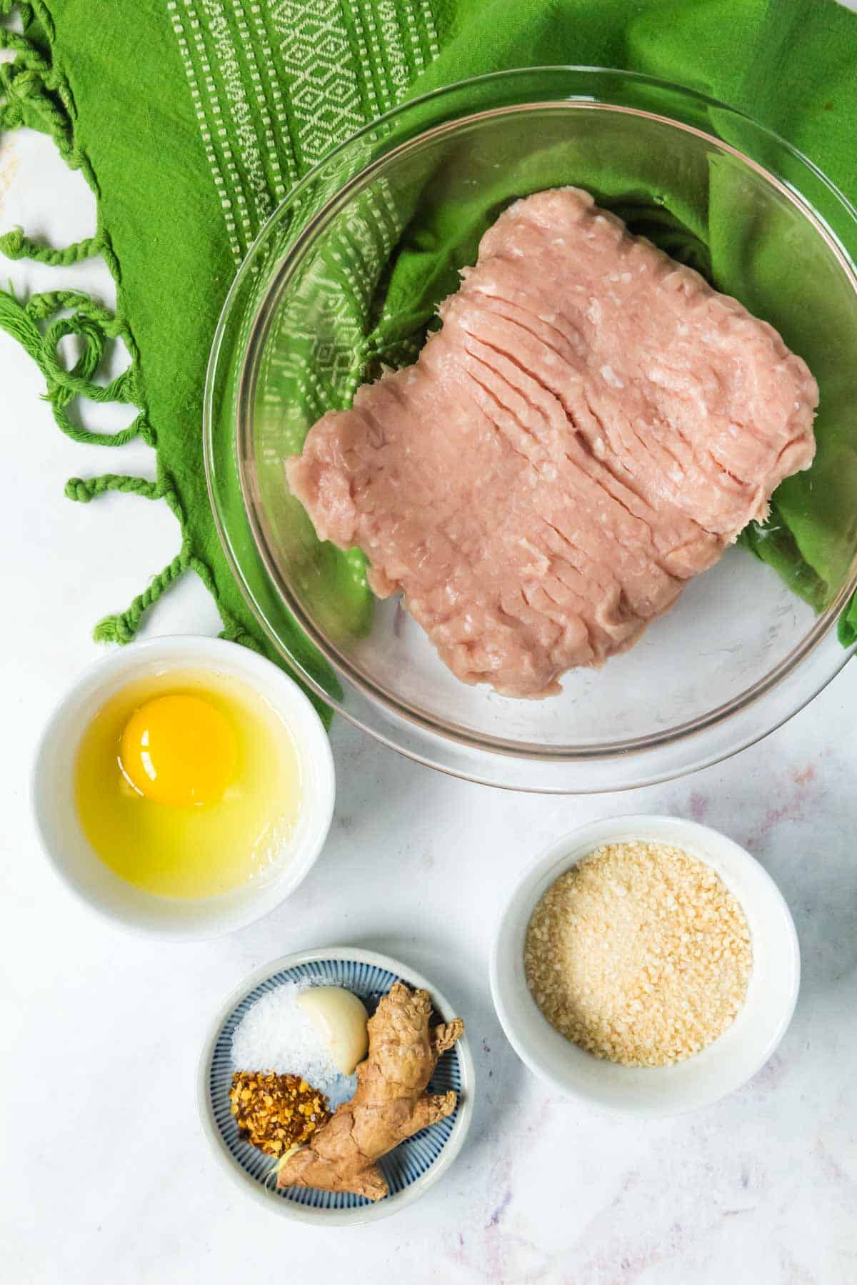 The ingredients for chicken meatballs: Ground chicken breast, breadcrumbs, seasoning, and egg.