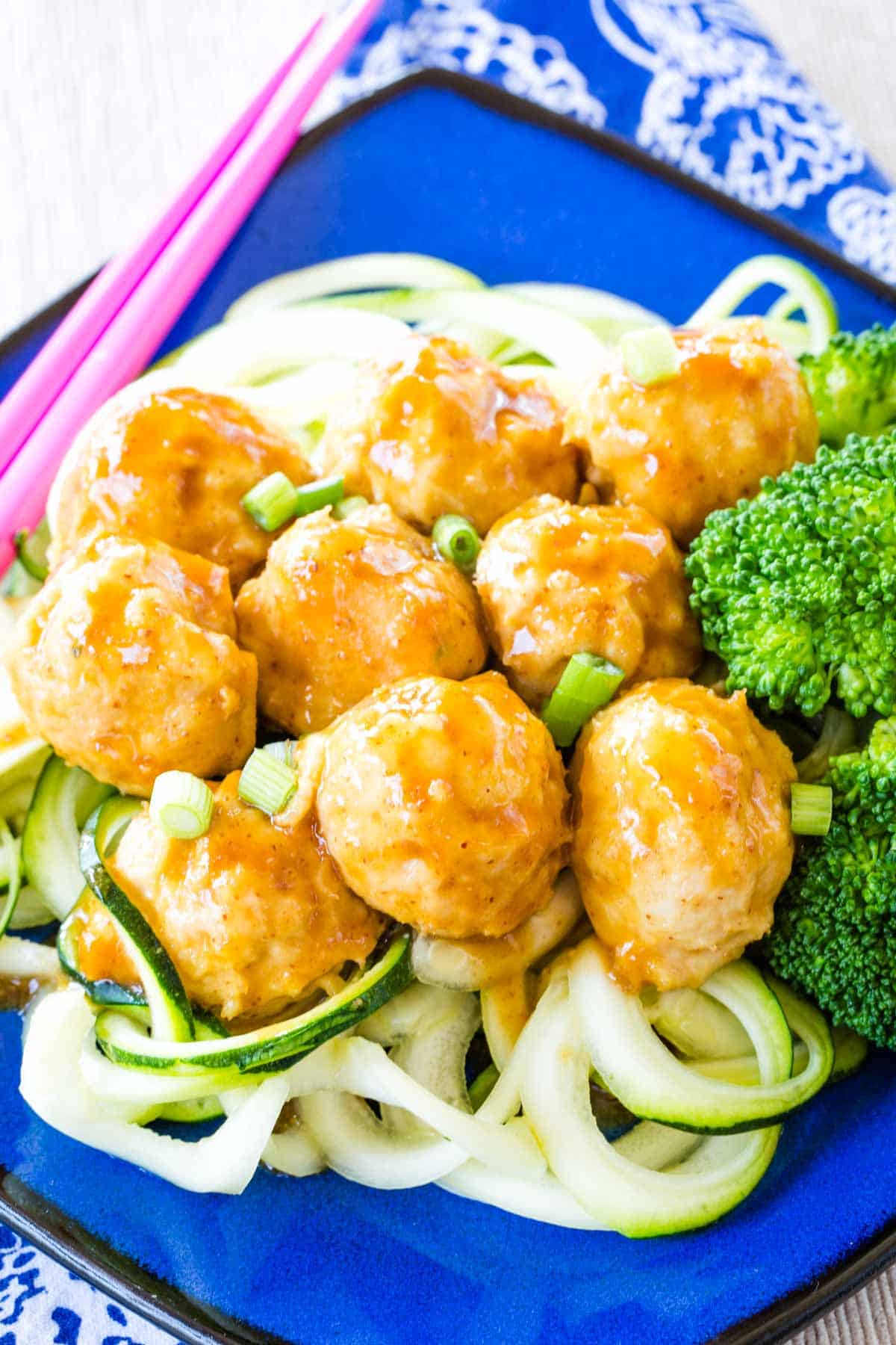 General Tso's Chicken Meatballs served over zoodles and steamed broccoli.