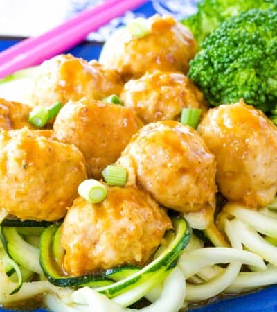 General Tso's Chicken Meatballs served over zoodles and steamed broccoli.