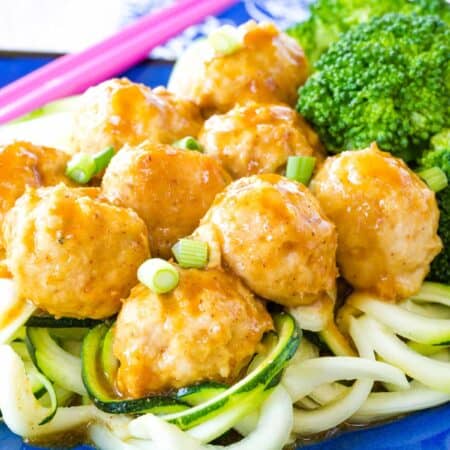 General Tso's Chicken Meatballs served over zoodles and steamed broccoli.