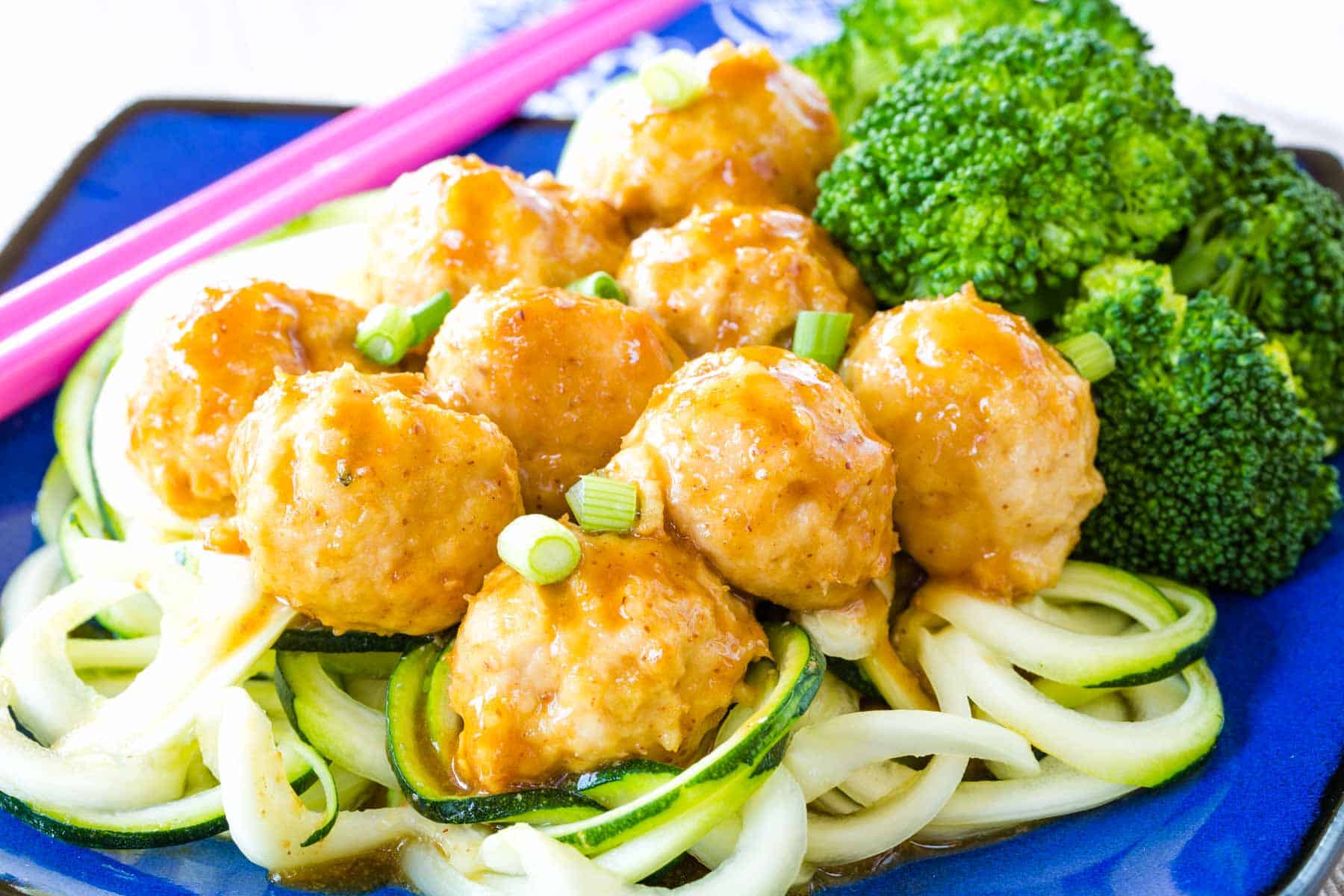 General Tso's Chicken Meatballs served over zoodles and steamed broccoli.