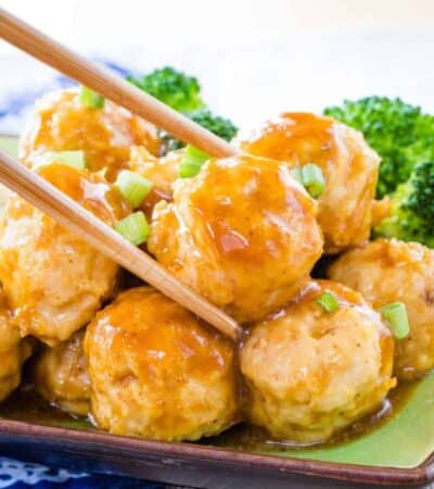 Chopsticks grabbing an Asian chicken meatball
