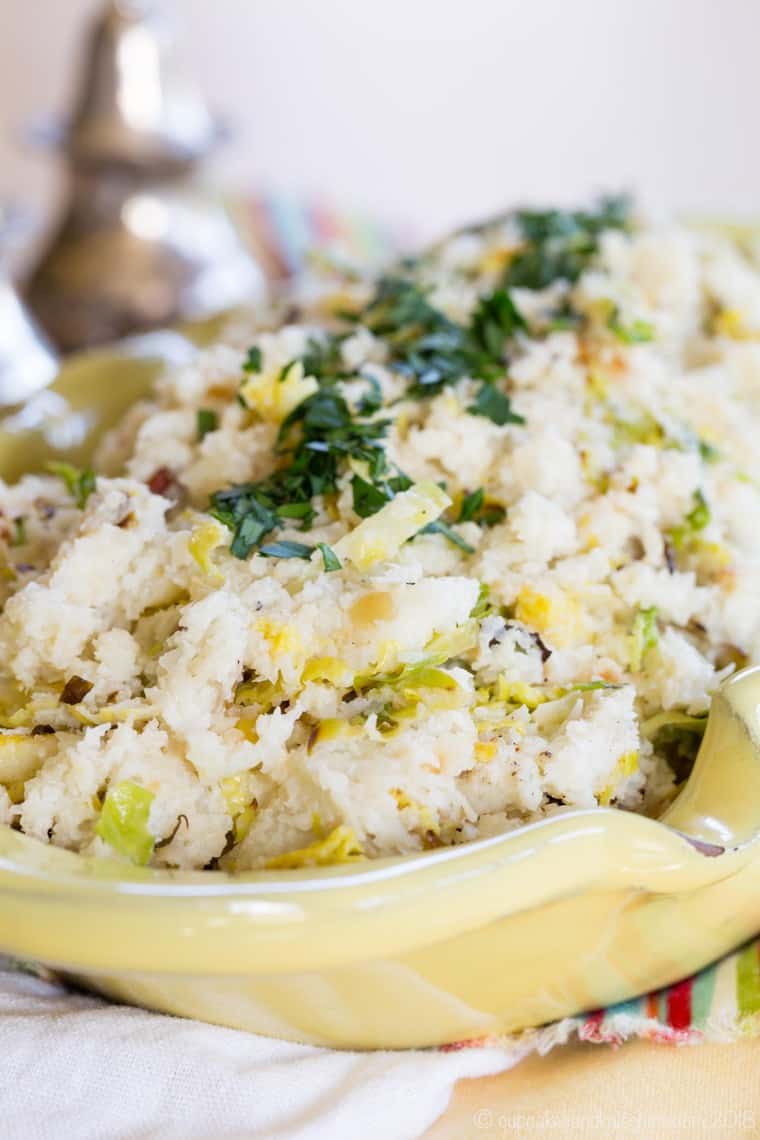 Cauliflower colcannon in a serving bowl garnished with chives.