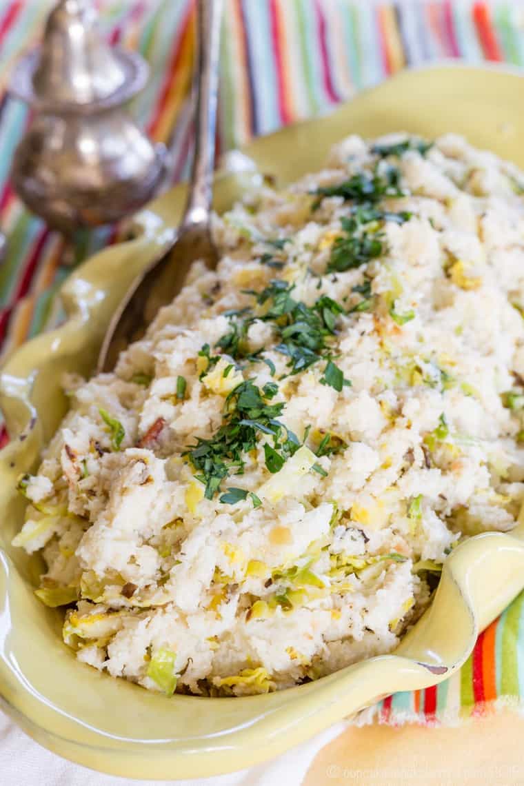 Cauliflower colcannon in a serving bowl with a metal spoon.