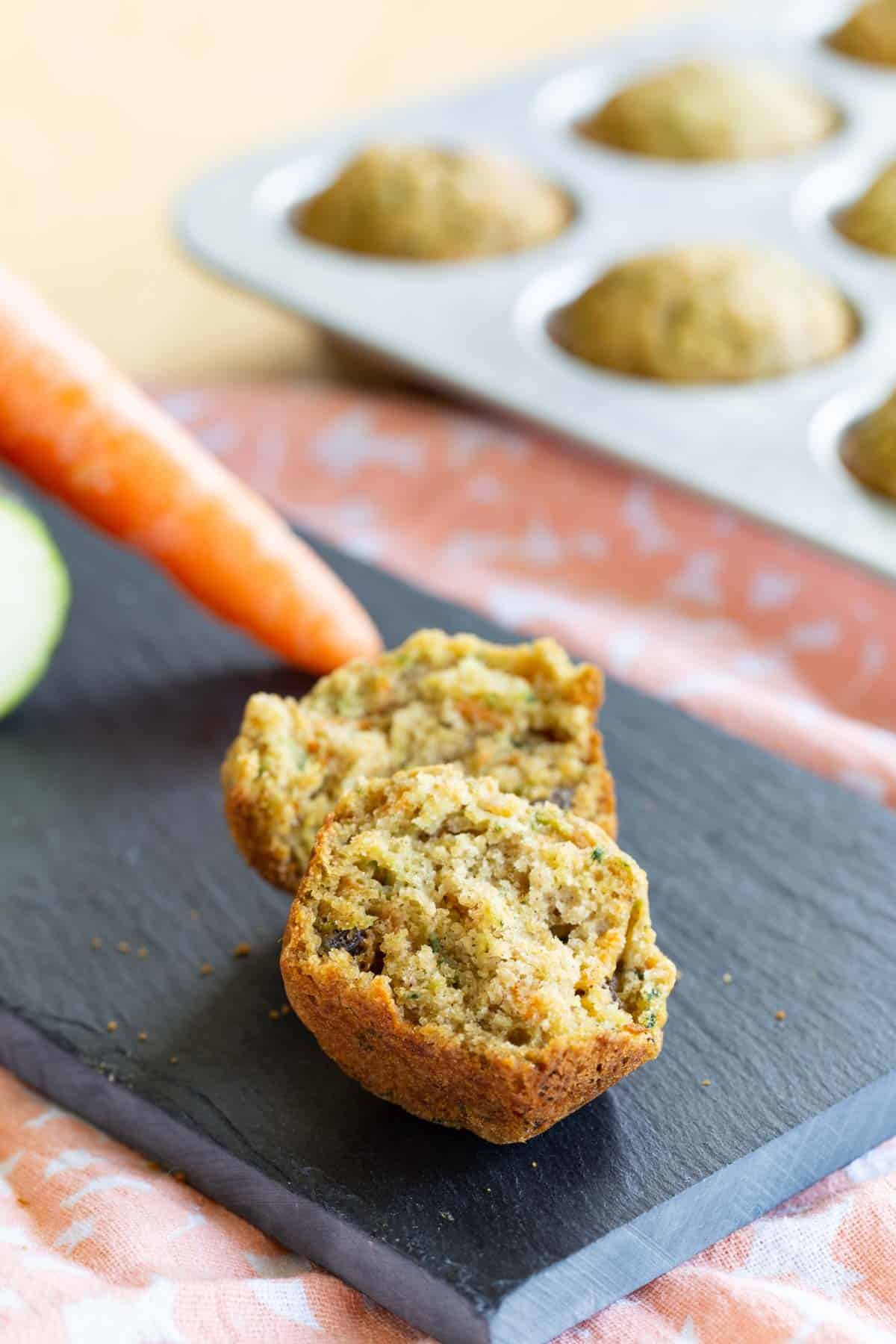 one gluten free mini muffin broken in half on a slate platter