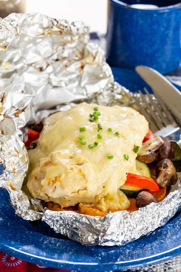 Maple Dijon Chicken Foil Packs with sweet potatoes, mushrooms, red peppers, and zucchini on a blue plate