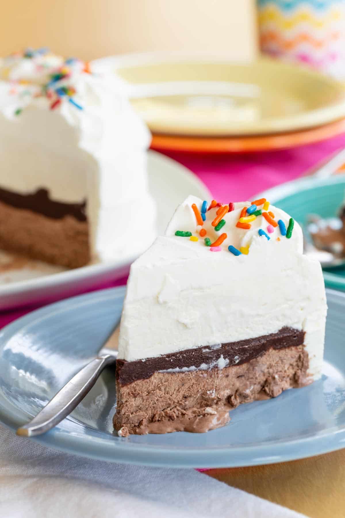 A slice of homemade ice cream cake with layers of vanilla and chocolate no-churn ice cream and fudge