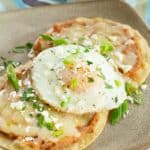Breakfast tostadas topped with refried beans and a fried egg.