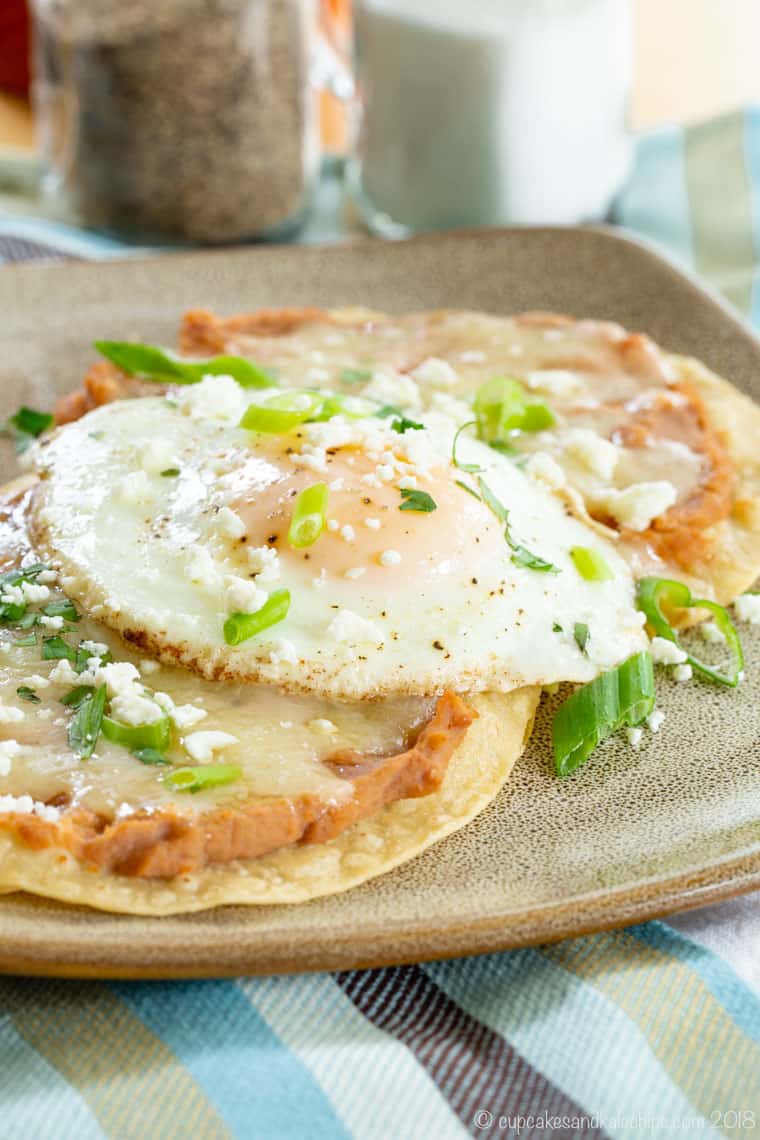 Breakfast tostadas topped with refried beans and a fried egg.